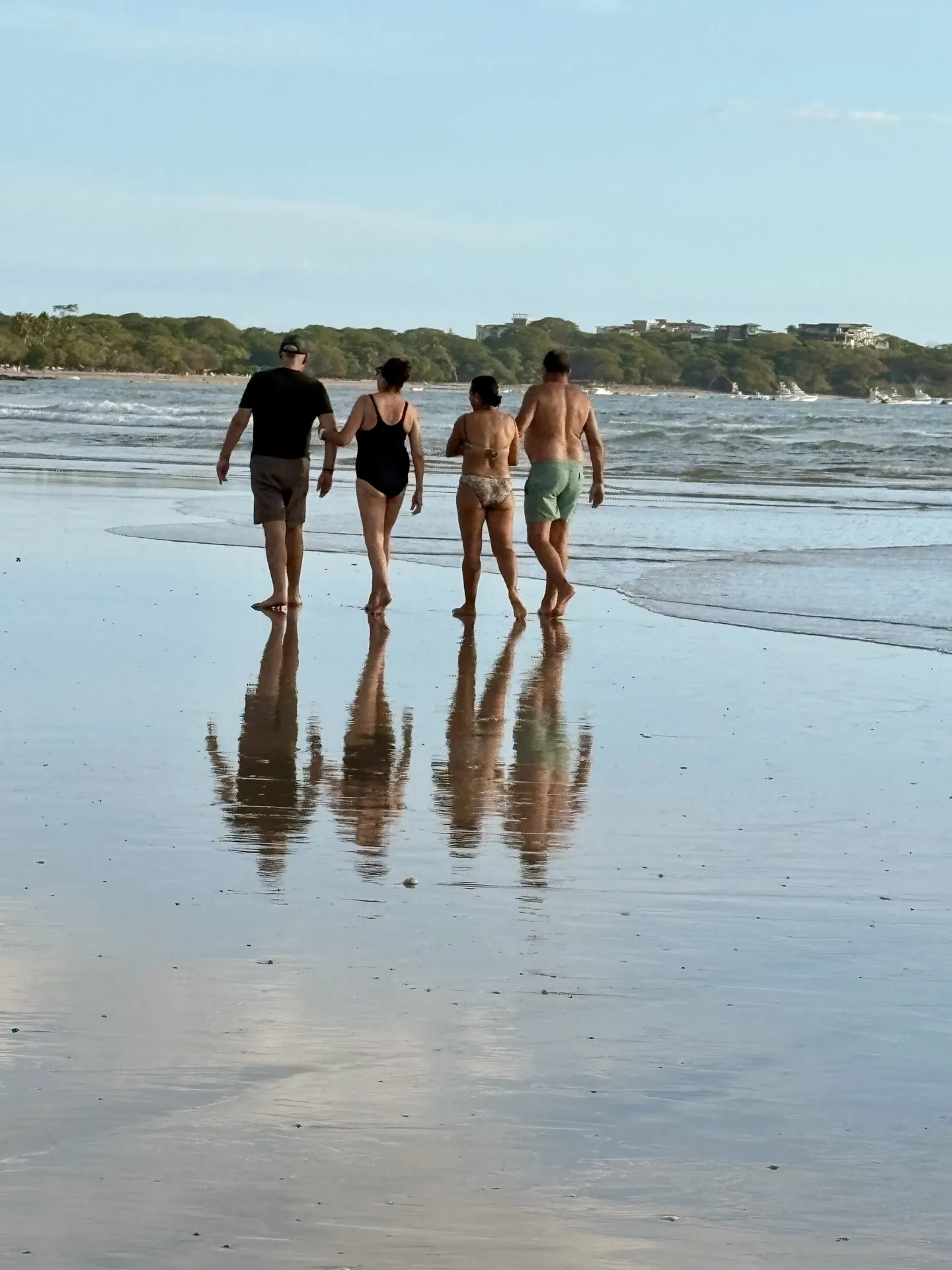 Amis marchant sur le sable mouillé qui fait miroir