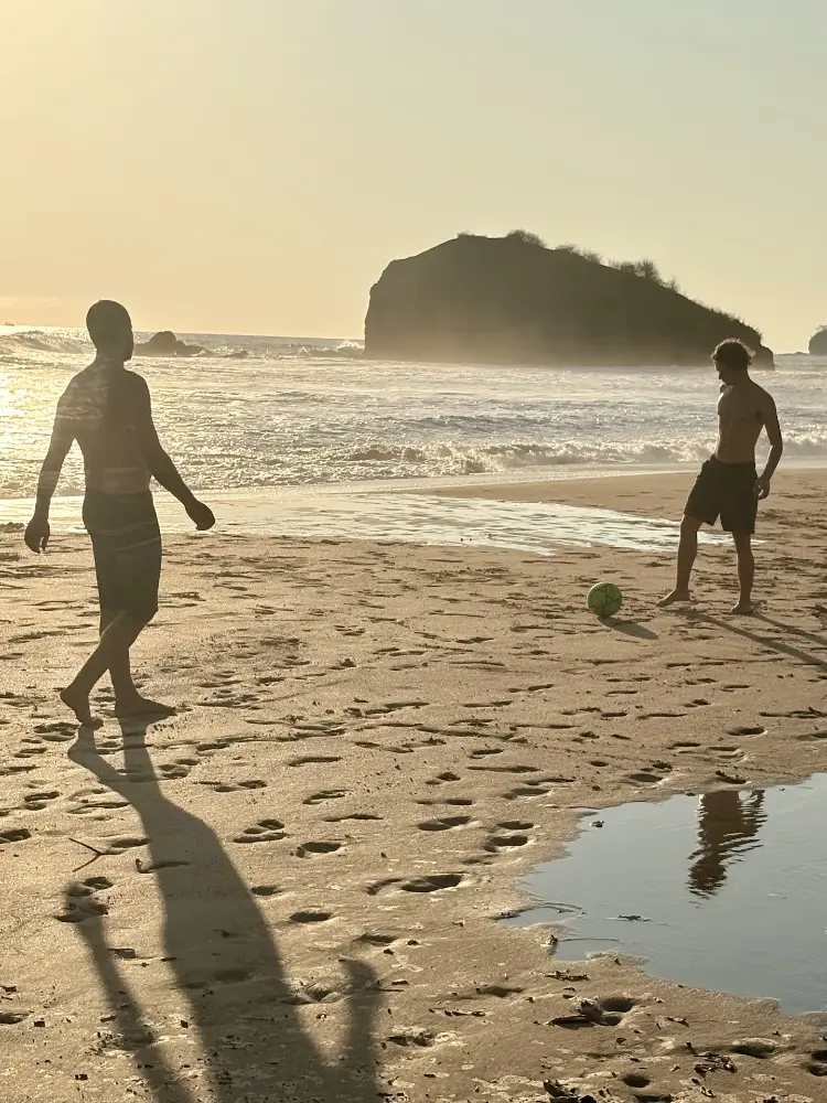 Soccer de plage à l’heure dorée, avec le gros rocher derrière