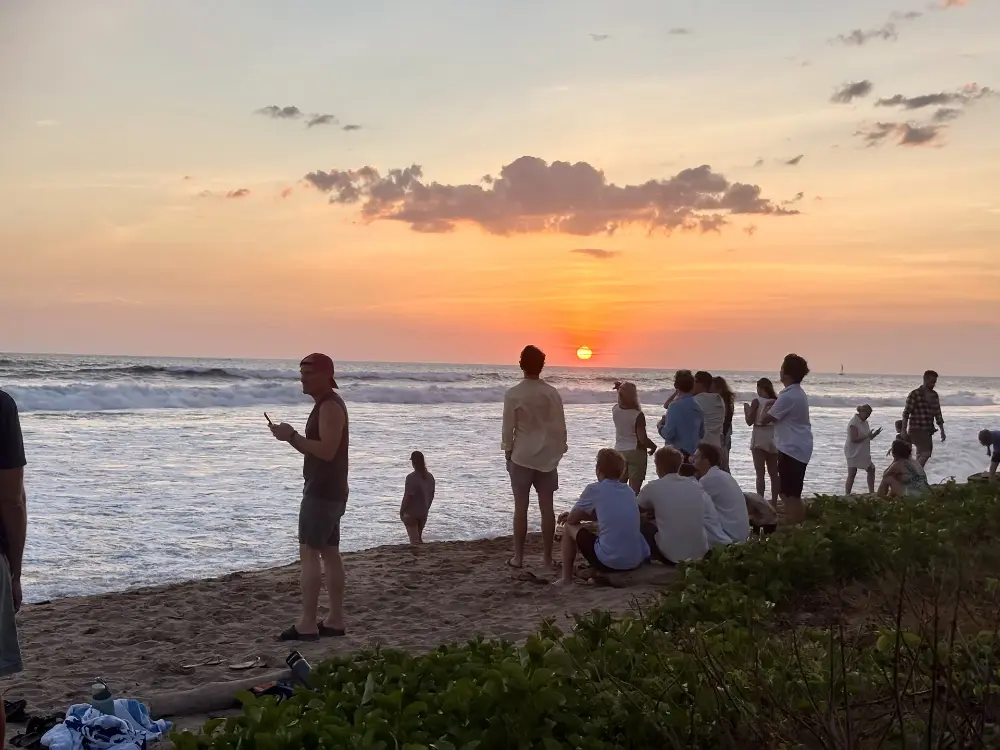 Voisins et visiteurs réunis sur la plage pour regarder le coucher du soleil