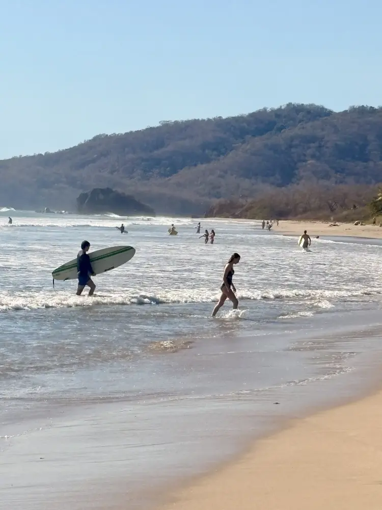 Surfeur avec sa planche longue entrant dans les vagues à Playa Grande