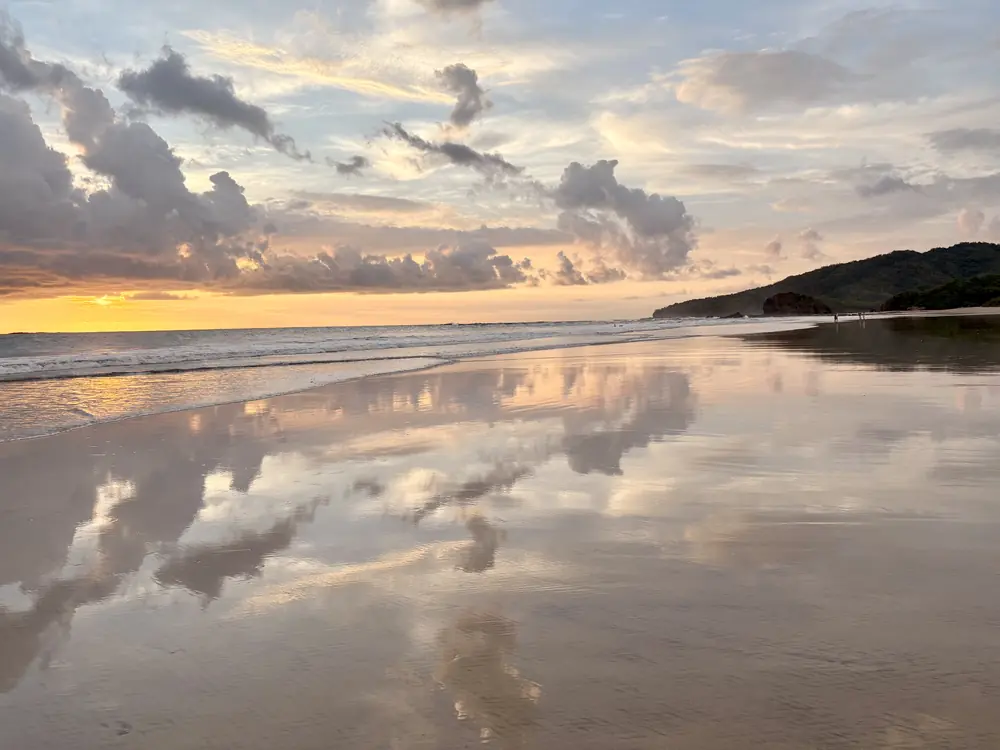 Sunset clouds doubled on wet sand